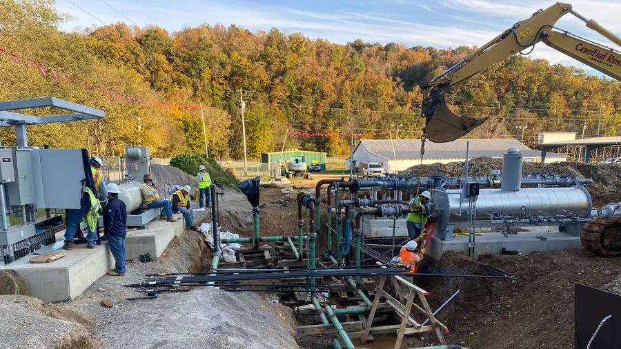 Crews building a natural gas meter station, with station piping, equipment, and concrete foundations in place