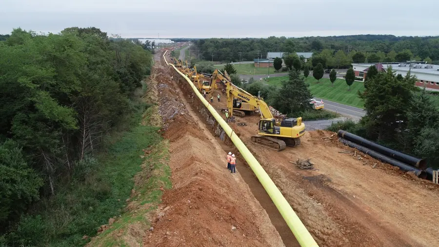 Large-diameter coated pipe staged along a hillside right-of-way
